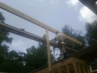 Carpenter setting a ridge beam over a new addition frame — Ice Dam Removal by Roofing Brothers in Bigelow