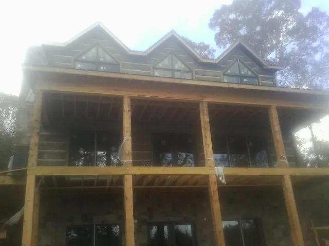 Dormers and porch framing on a large log home under construction — Roof Coating work by our crew in Bigelow