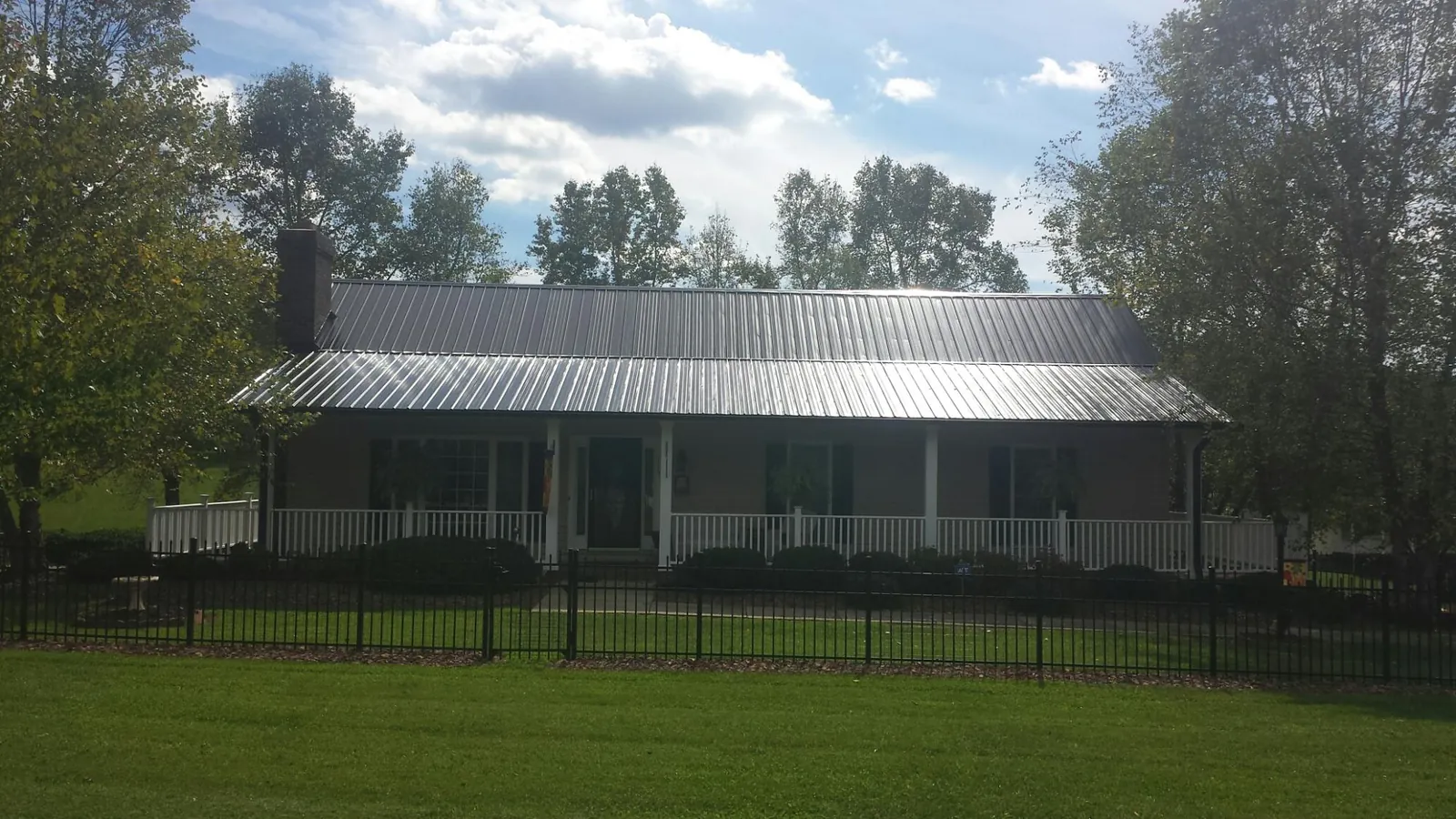 Gray metal roof on a brick ranch with a full width front porch — Gutter Guard Installation work by our crew in Bigelow