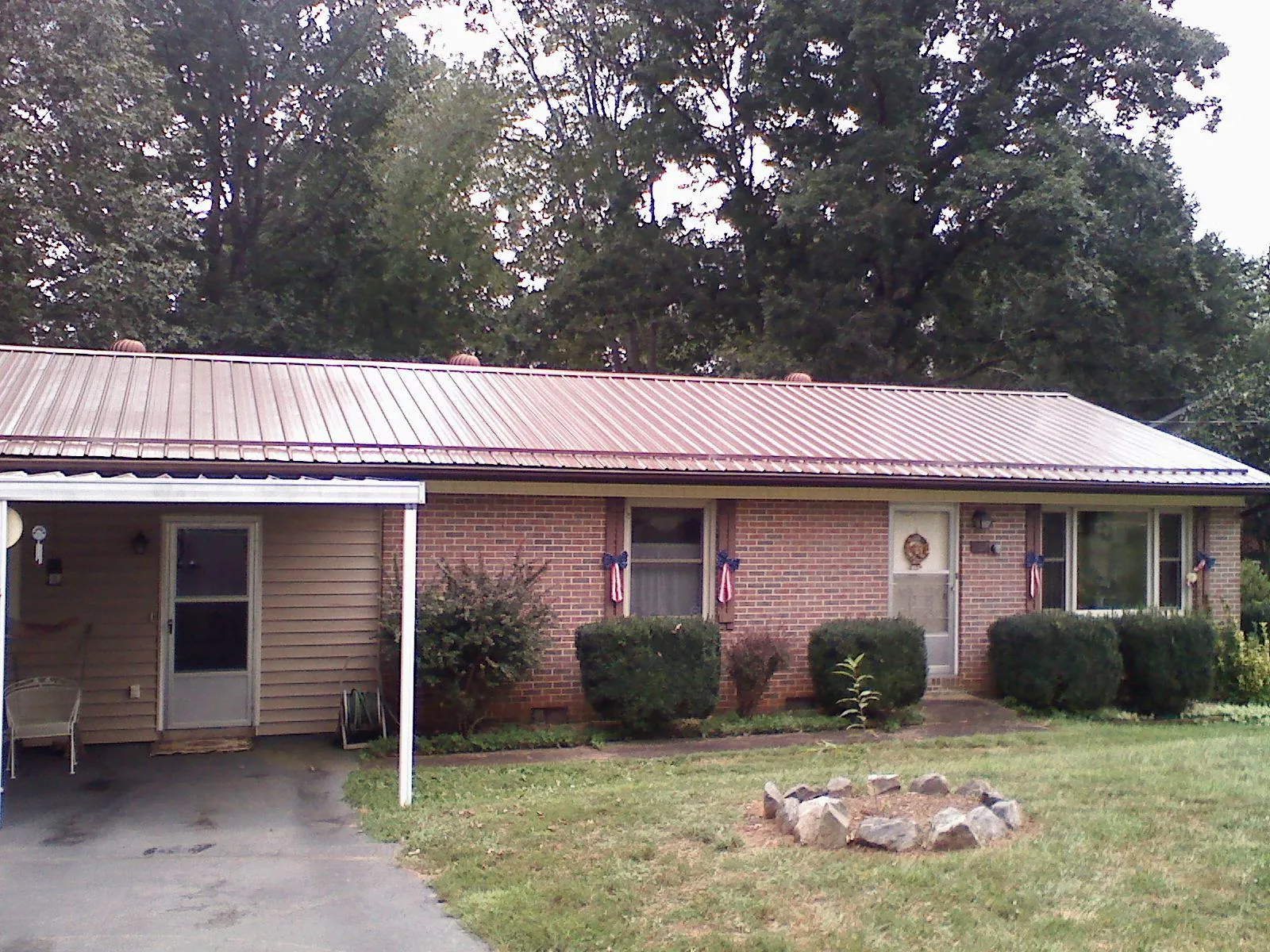 Bronze metal roof and carport on a brick ranch home — Roof Repair work by our crew in Bigelow